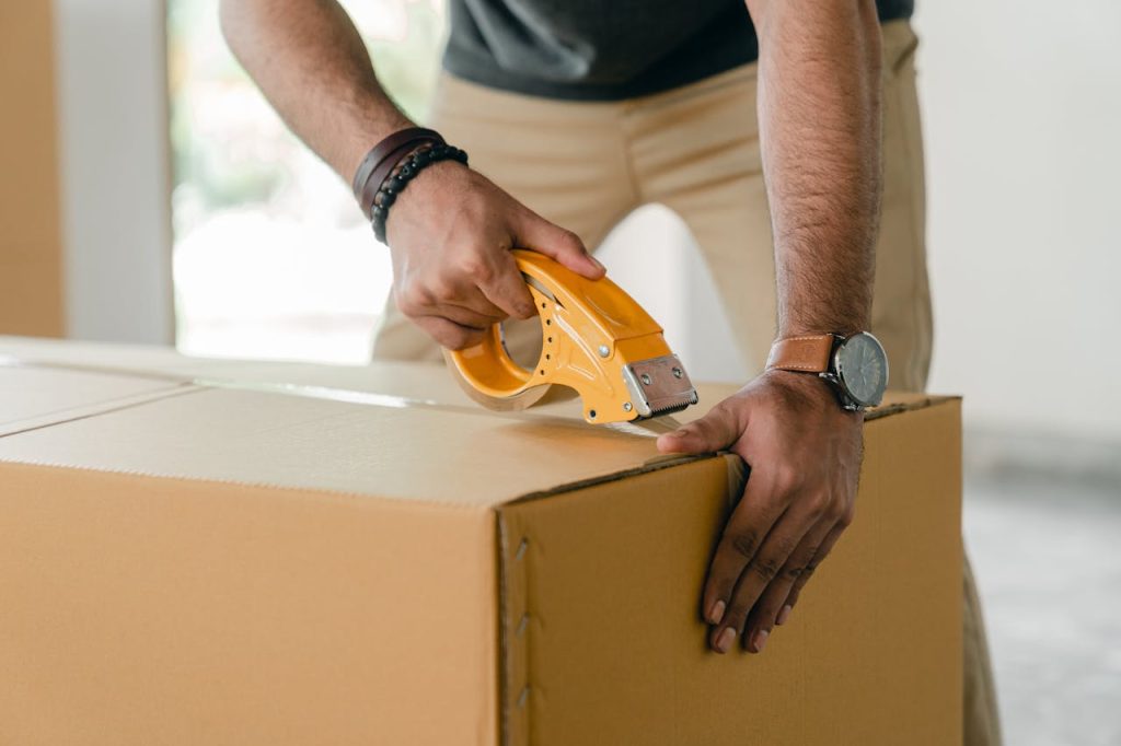 crop-man-taping-carrying-box-with-scotch-4246120 Crop faceless young male with wristwatch using adhesive tape while preparing cardboard box for transportation